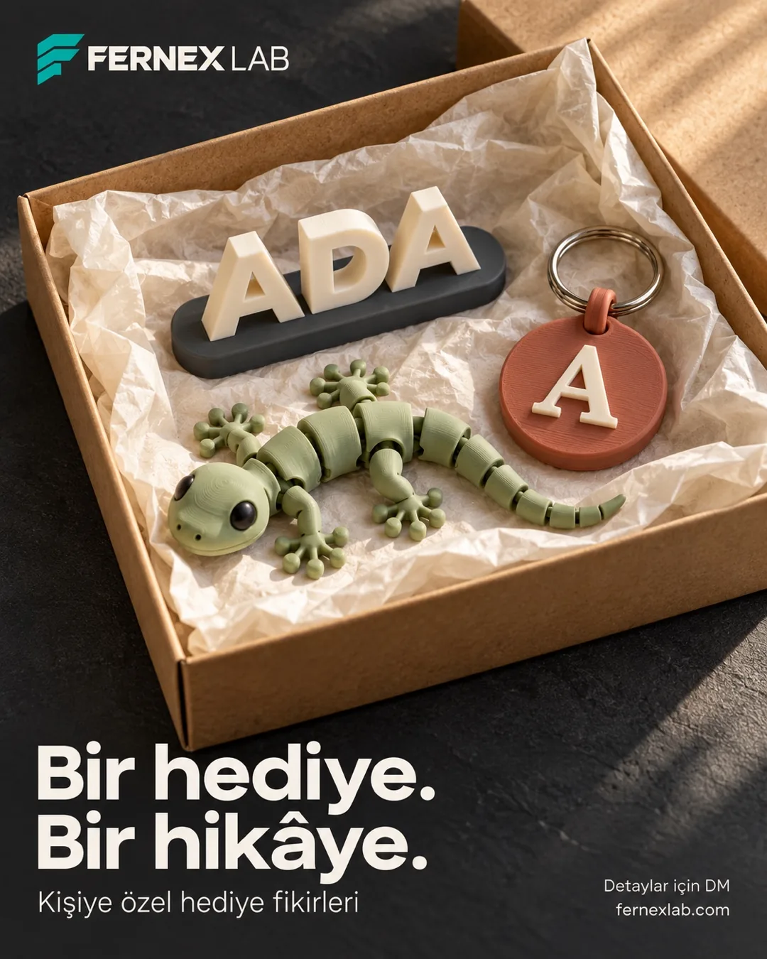 A kraft gift box with an ADA nameplate, an articulated gecko and an A-initial keyring; Turkish headline “A gift, a story”.